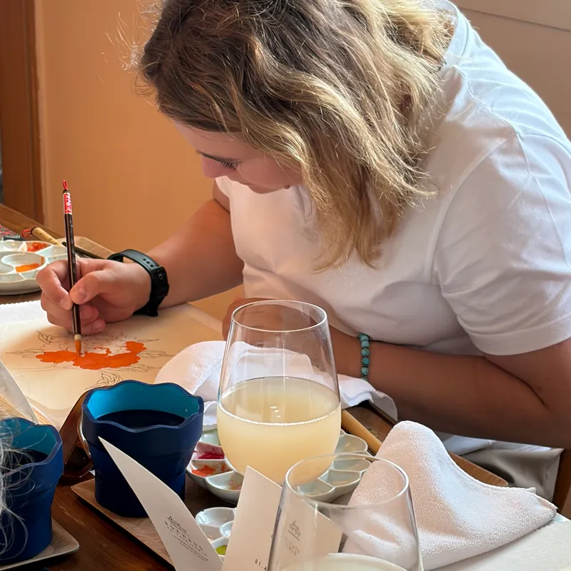 A guest brushing red pigment onto a Minhwa piece