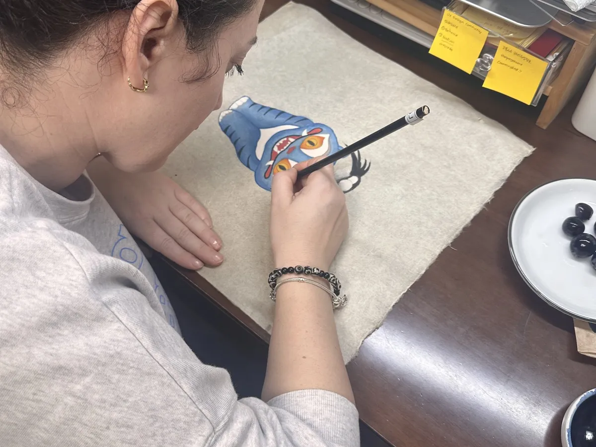 A hand painting the face of a tiger