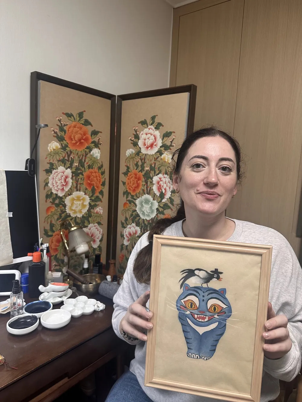 A participant holding the framed tiger painting they made