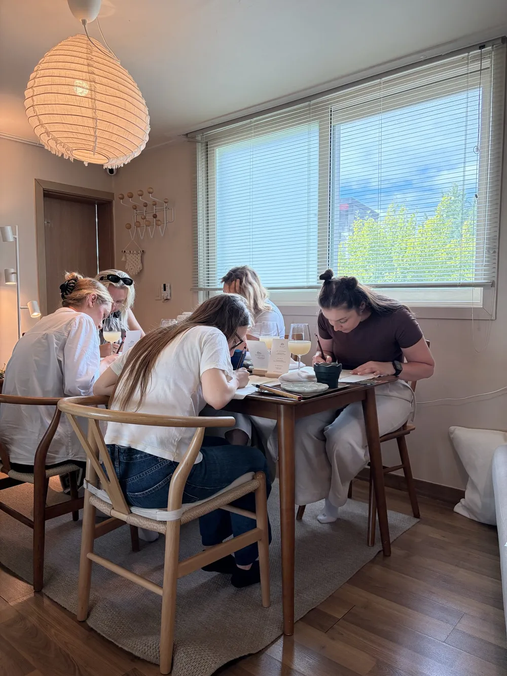 Guests painting together at a table under a paper lantern